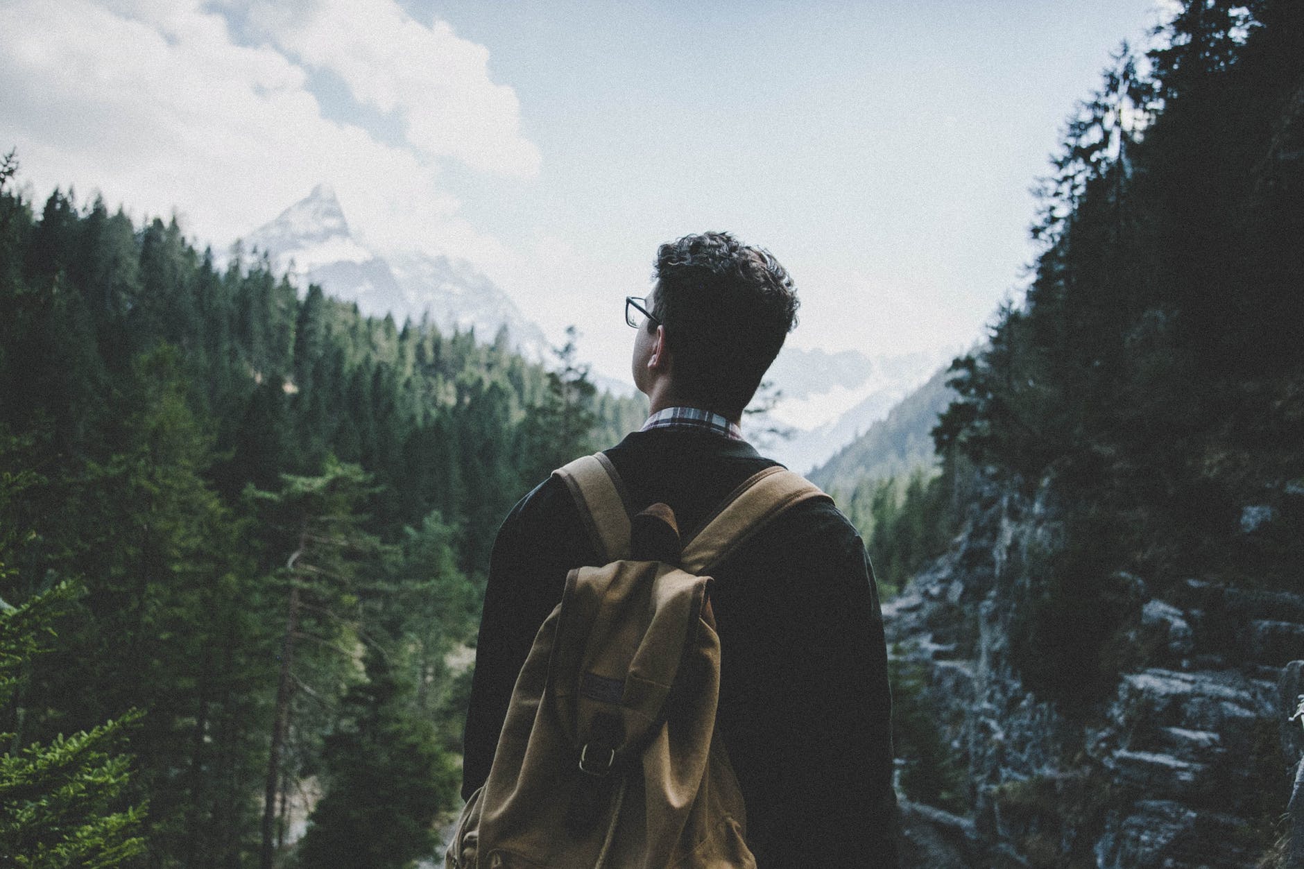 man standing on rocky mountain under white cloudy sky